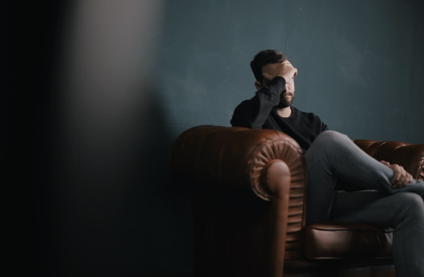 Person sitting alone with their hand covering their face