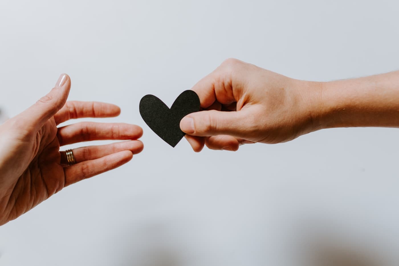 A hand reaching toward a black paper heart