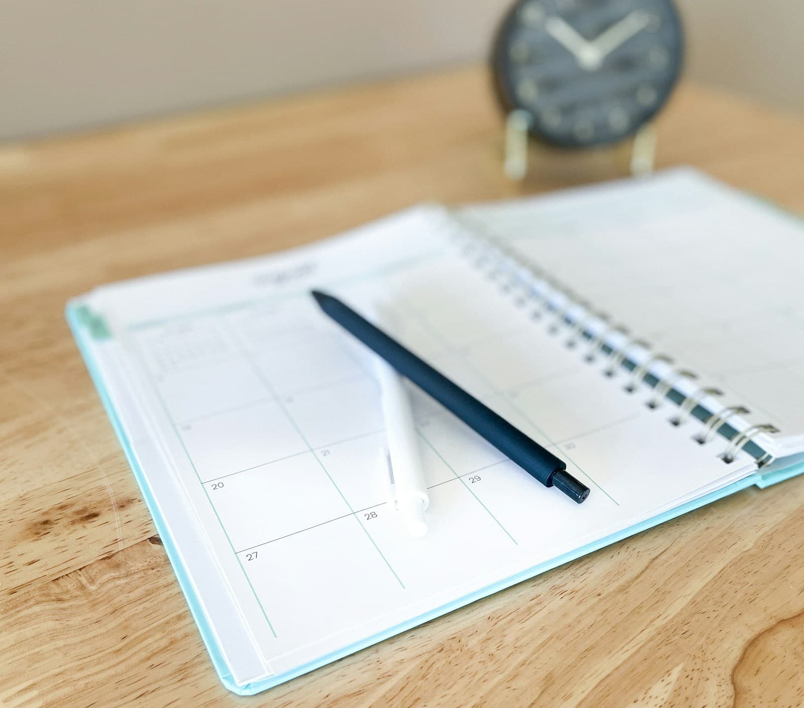 Open planner and pen on an organised wooden desk