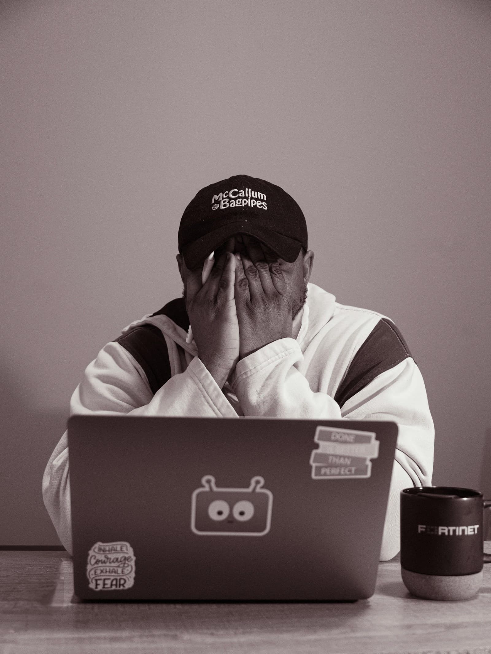 Overwhelmed person covering their face while seated at a laptop